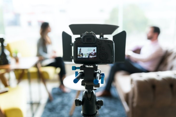 Looking through a camera lens at two people in a living room